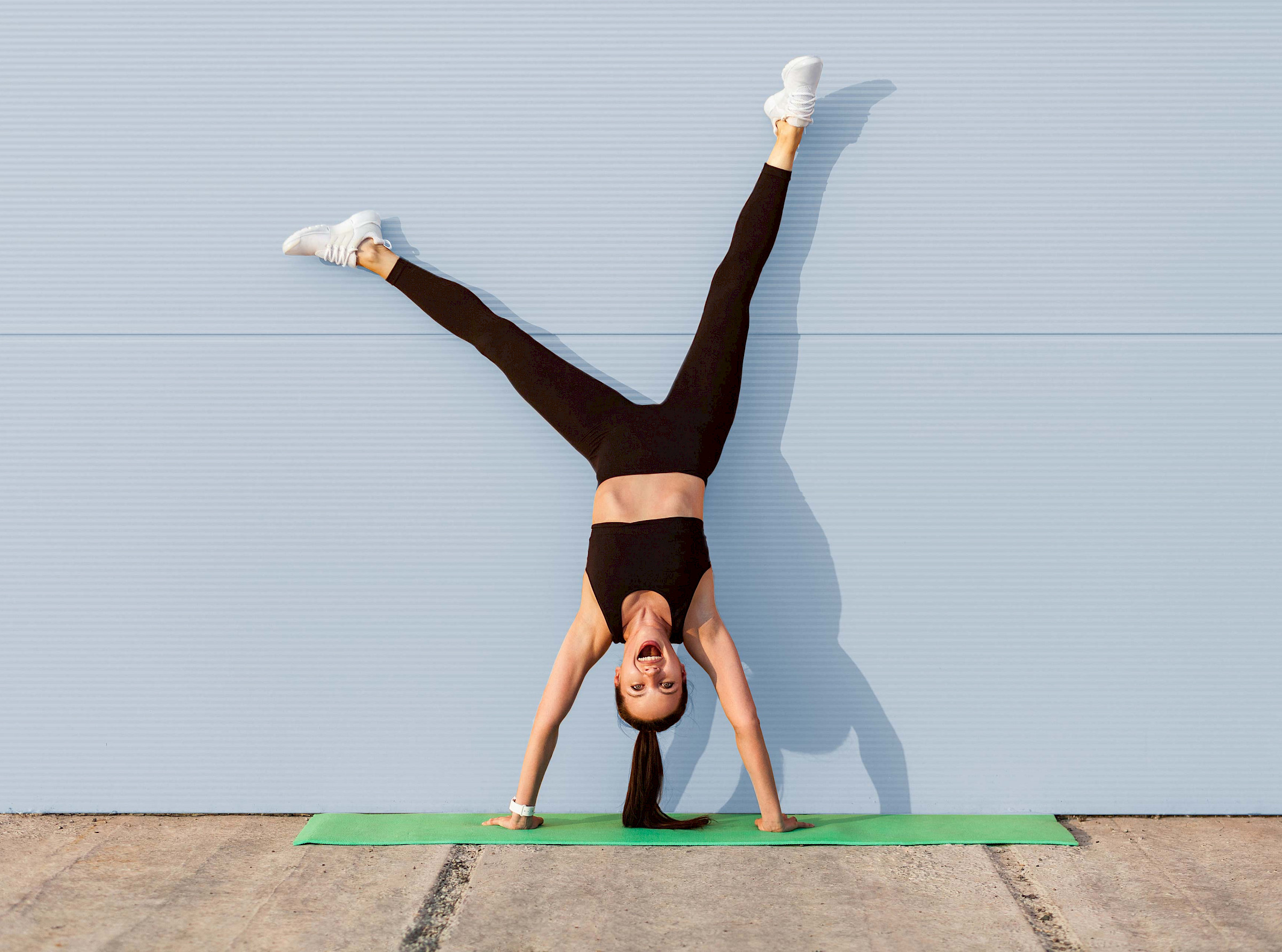 Frau macht Handstand auf einer Gymnastikmatte